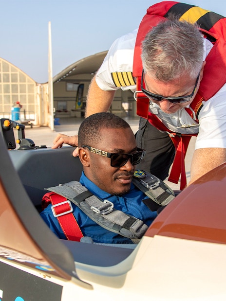 Pilot assisting passenger in cockpit for GFORCE Aerobatic Passenger Experience.