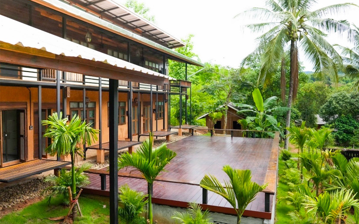 Lodge with wooden deck surrounded by lush greenery at Elephant Jungle Sanctuary, Chiang Mai.