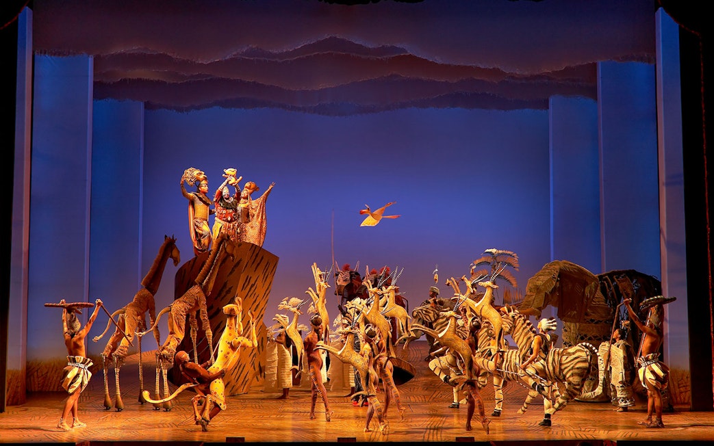 Stage performance of The Lion King with actors in animal costumes.