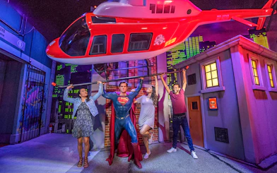 Tourists posing with Superman wax statue holding helicopter at Madame Tussauds.