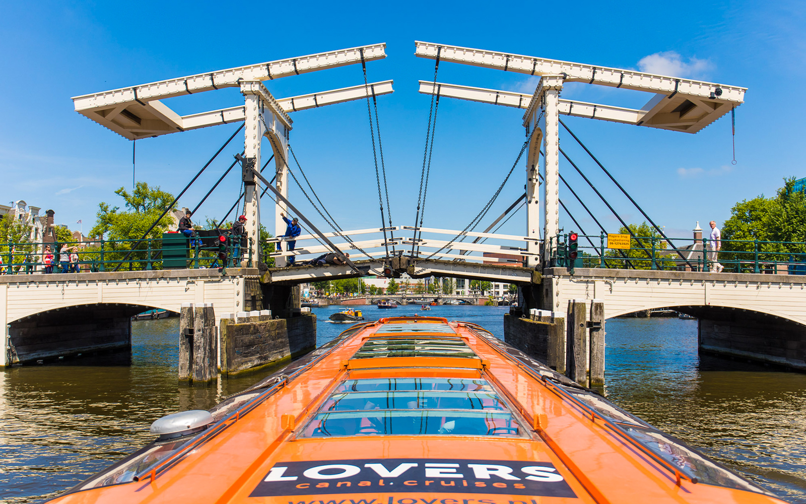 Canal cruise boat approaching Magere Brug in Amsterdam.