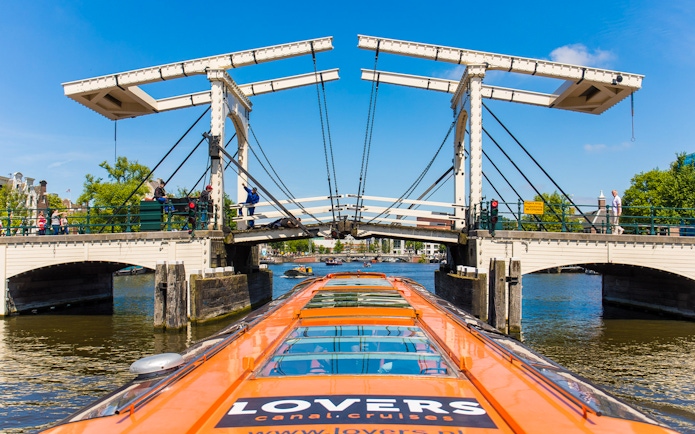 Canal cruise boat approaching Magere Brug in Amsterdam.