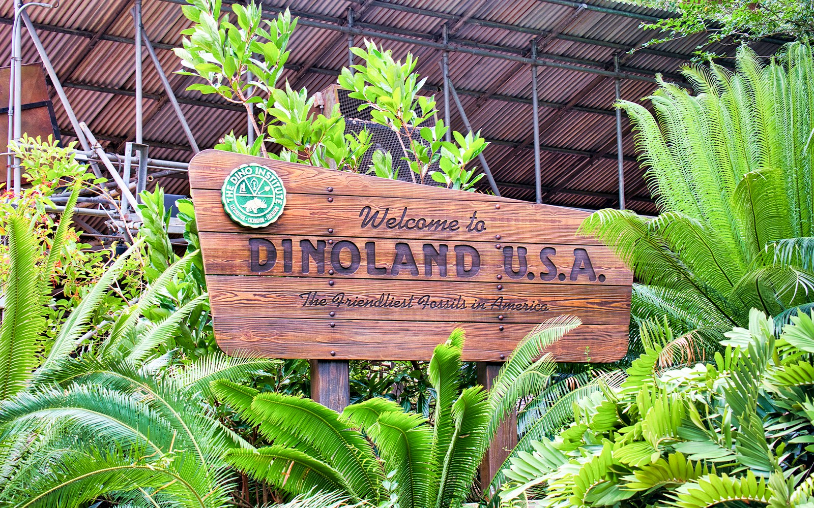 Dinoland USA entrance sign at Walt Disney's Animal Kingdom, Orlando, surrounded by greenery.