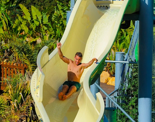 Tourist descending waterslide at Zoomarine Algarve water park, Portugal.