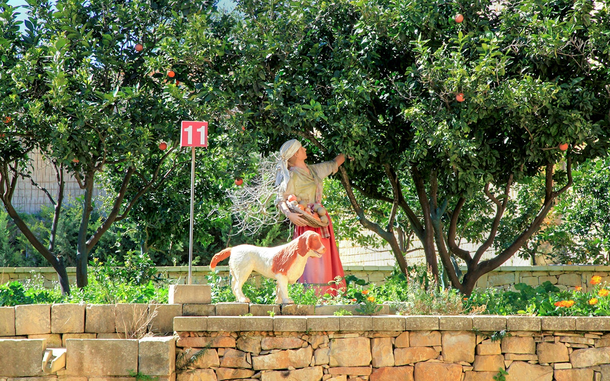 Woman statue with fruit basket and dog under orange trees at Limestone Heritage Park.
