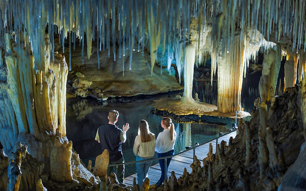 Visitors observe stalactites and stalagmites over water in Lake Cave, Margaret River.