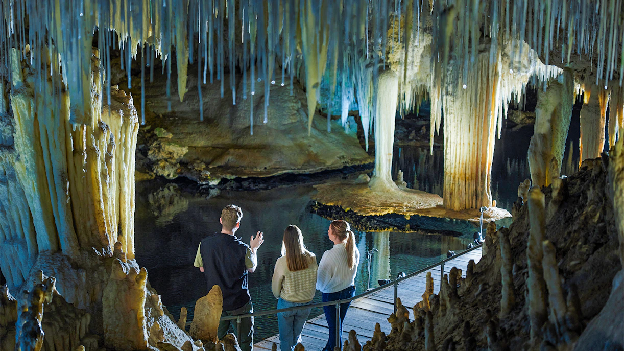 Visitors observe stalactites and stalagmites over water in Lake Cave, Margaret River.