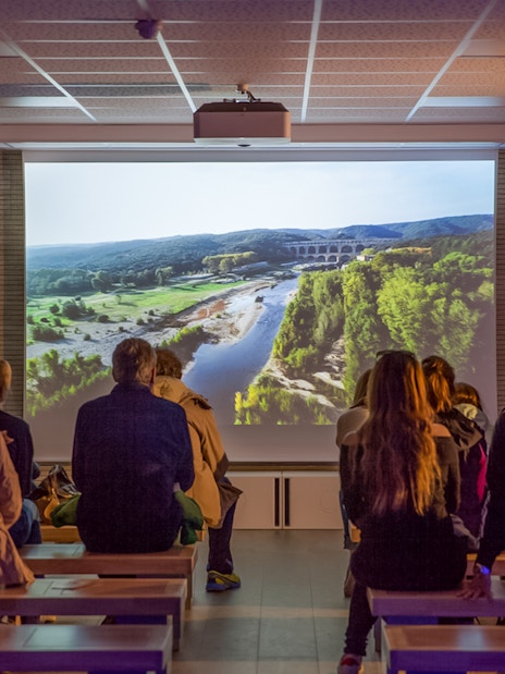 Visitors watching a Pont du Gard documentary in a museum cinema.