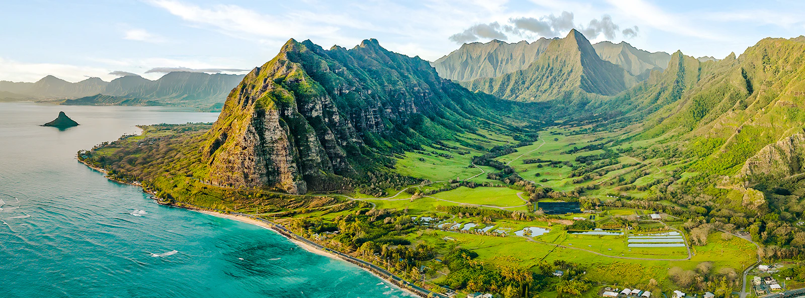 Aerial view of Kualoa Ranch, Hawaii with lush green mountains and coastline.
