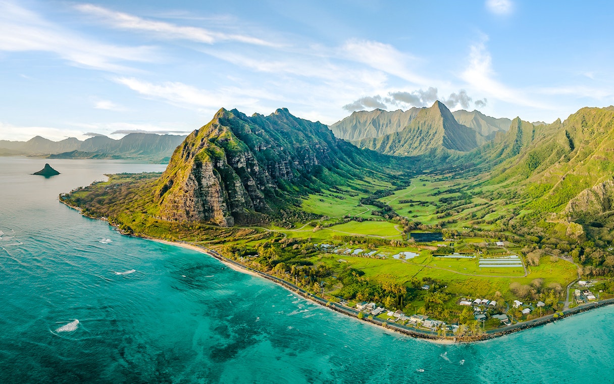 Aerial view of Kualoa Ranch, Hawaii with lush green mountains and coastline.