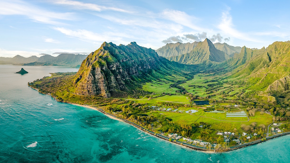 Aerial view of Kualoa Ranch, Hawaii with lush green mountains and coastline.