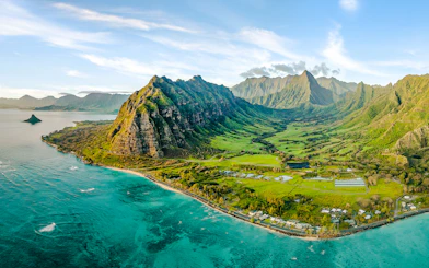 Aerial view of Kualoa Ranch, Hawaii with lush green mountains and coastline.
