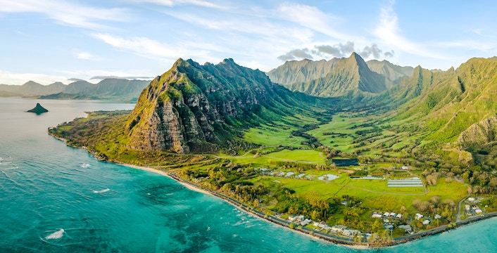 Aerial view of Kualoa Ranch, Hawaii with lush green mountains and coastline.