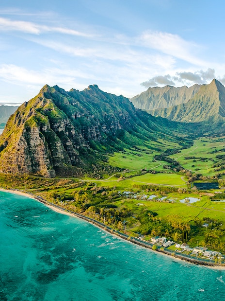 Aerial view of Kualoa Ranch, Hawaii with lush green mountains and coastline.