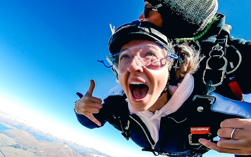 Skydiver tandem jumping over Mt Cook, New Zealand, with clear blue sky.