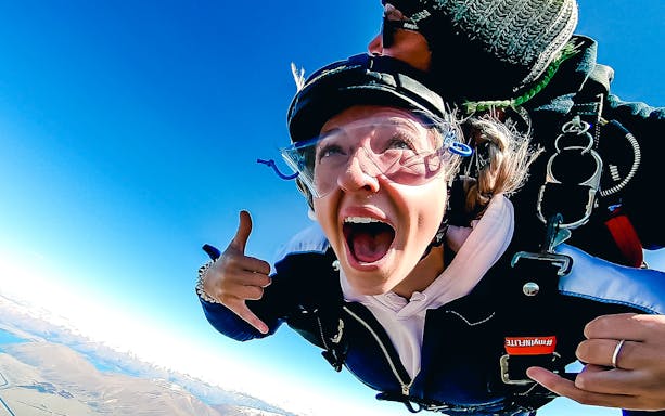 Skydiver tandem jumping over Mt Cook, New Zealand, with clear blue sky.