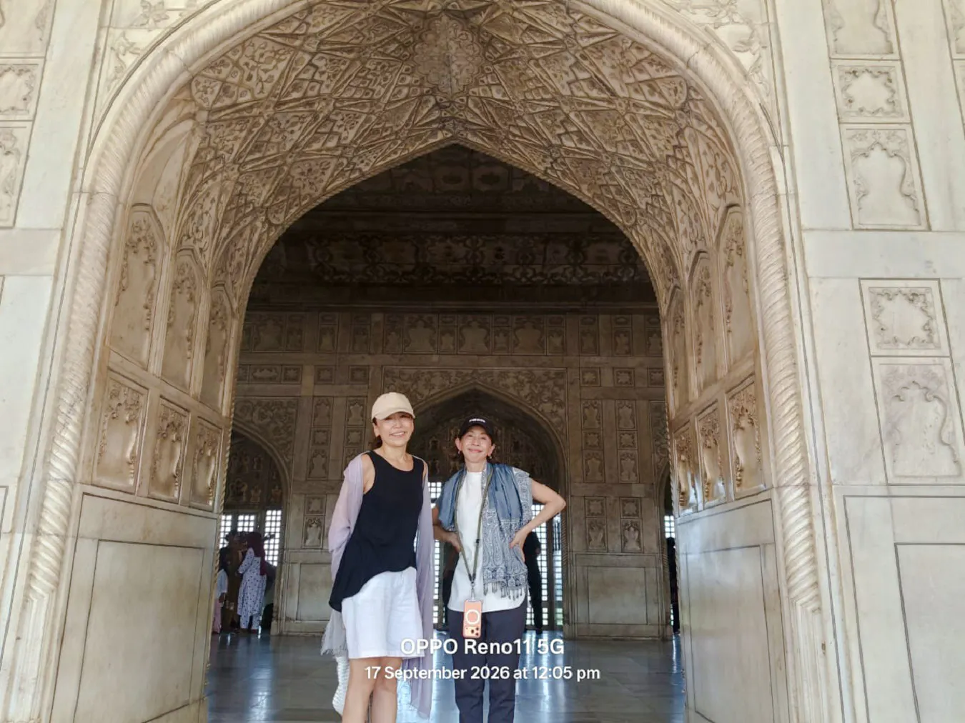 Visitors inside the intricately carved marble archway of the Taj Mahal, Agra.
