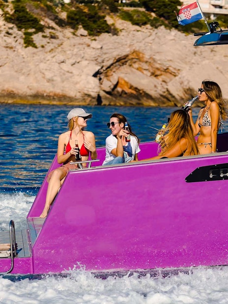 Boat ride with friends near Dubrovnik, Croatia, enjoying drinks on a purple boat.