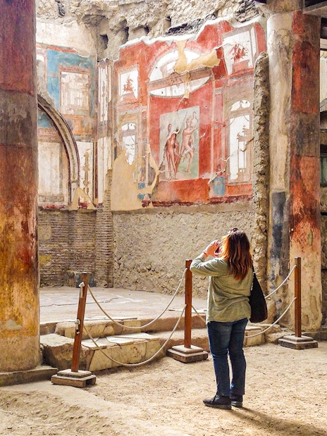 Tourist photographing frescoes at College of the Augustales, Herculaneum.