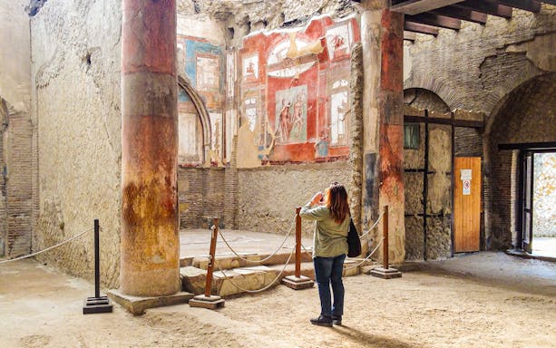Tourist photographing frescoes at College of the Augustales, Herculaneum.