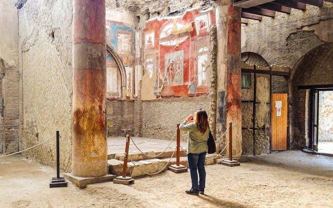 Tourist photographing frescoes at College of the Augustales, Herculaneum.