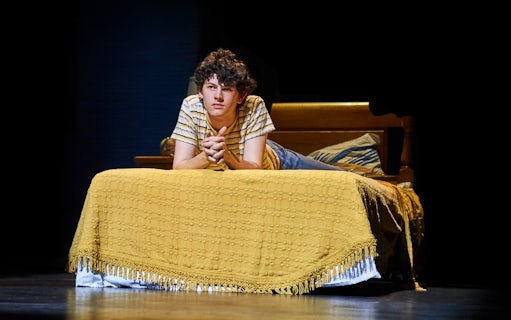 Young person lying on a bed, scene from "Almost Famous" stage production.