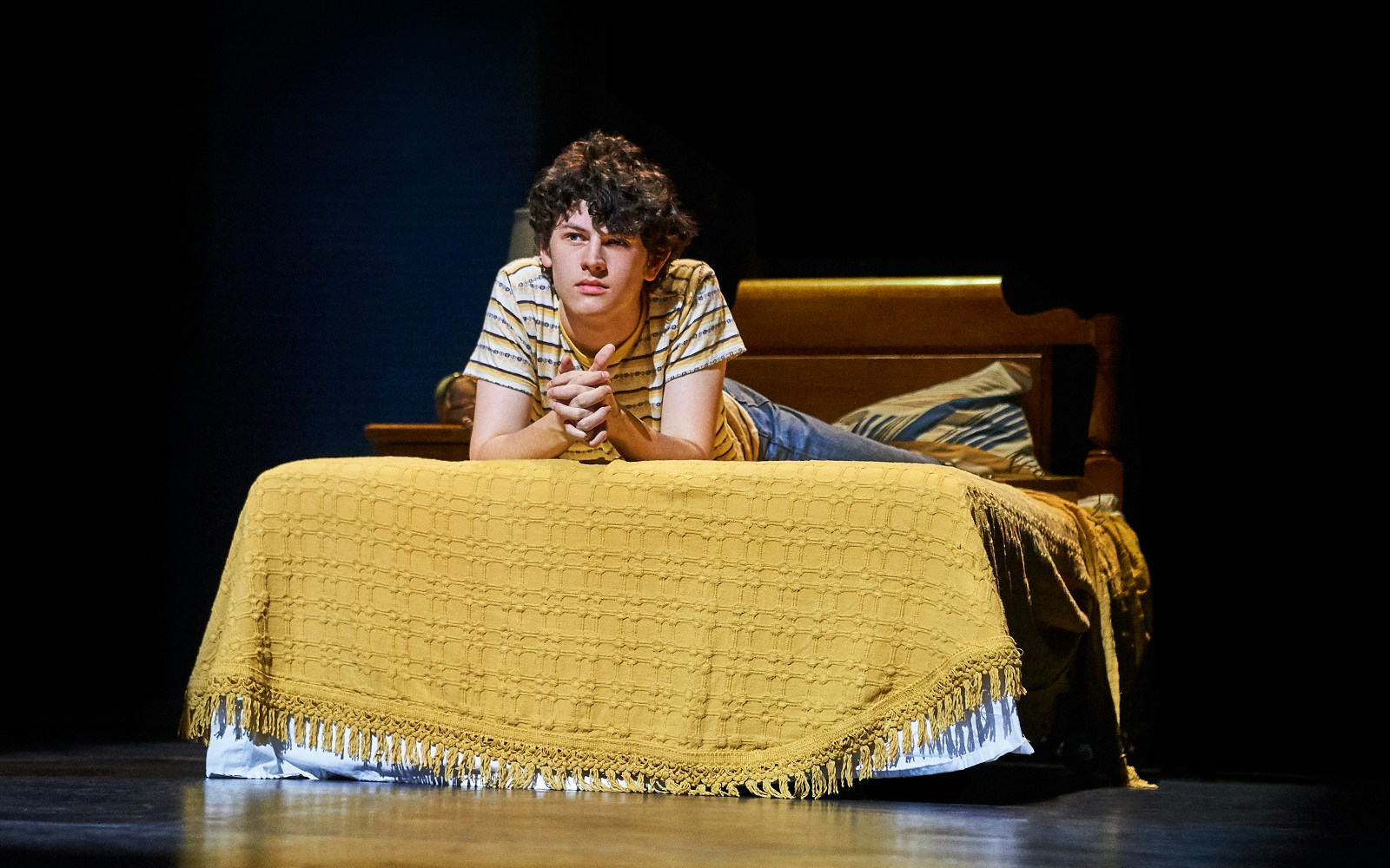 Young person lying on a bed, scene from "Almost Famous" stage production.