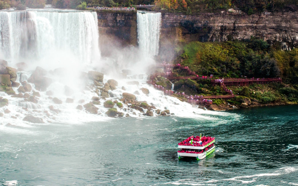 Tour boat approaching Niagara Falls with stairway visible on the gorge side.