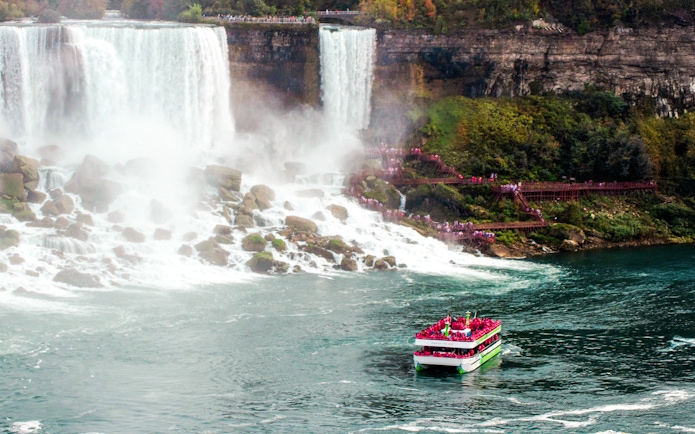 Tour boat approaching Niagara Falls with stairway visible on the gorge side.