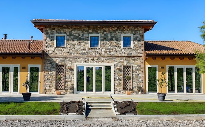 Stone building at Acetaia La Vedetta in Modena, Italy, with vineyard reflection in windows.