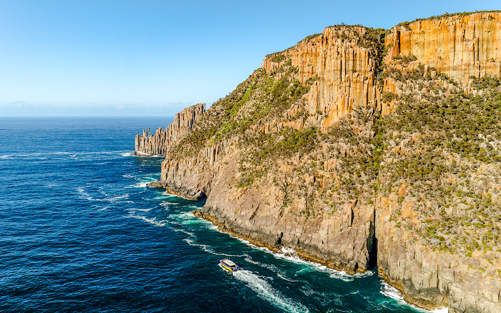 Cape Raoul coastline with cliffs and boat on the ocean, Tasmania.