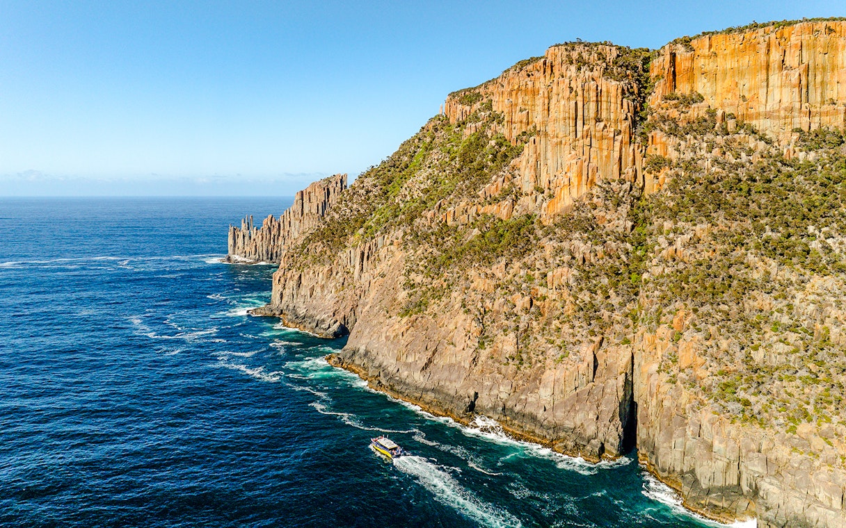 Cape Raoul coastline with cliffs and boat on the ocean, Tasmania.