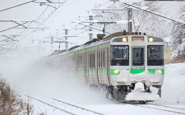 Train traveling through snowy landscape in Sapporo, Japan, part of 4-Day Sapporo-Noboribetsu Area Pass.