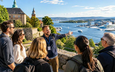 Tour guide with group overlooking Oslo fjord and Akershus Fortress.