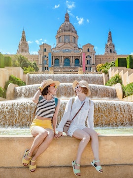 Two people sitting by the Magic Fountain with the National Art Museum of Catalonia in Barcelona.