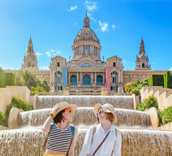 Two people sitting by the Magic Fountain with the National Art Museum of Catalonia in Barcelona.
