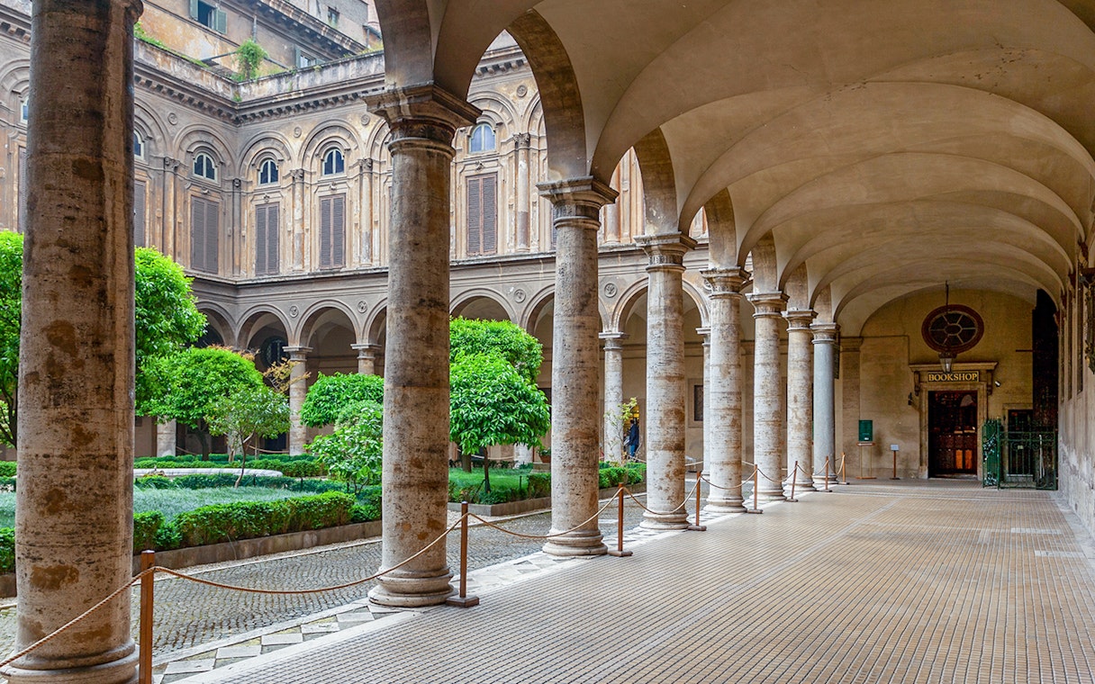 Doria Pamphilj Courtyard with stone columns and lush greenery in Rome.