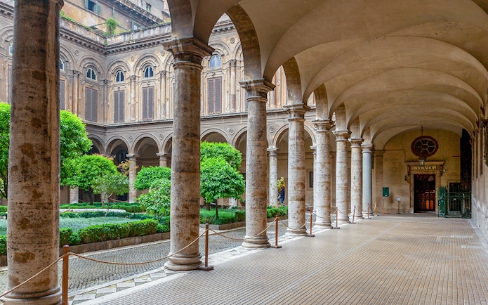 Doria Pamphilj Courtyard with stone columns and lush greenery in Rome.