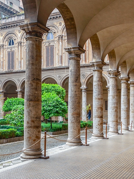Doria Pamphilj Courtyard with stone columns and lush greenery in Rome.