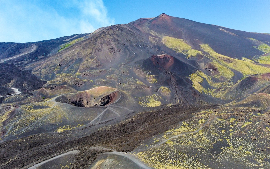 Mount Etna's volcanic landscape with craters and trails, viewed from a helicopter tour.