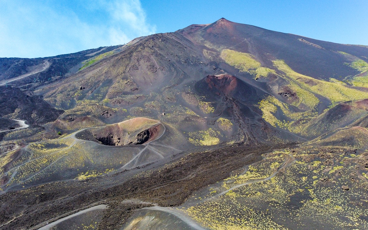 Mount Etna's volcanic landscape with craters and trails, viewed from a helicopter tour.