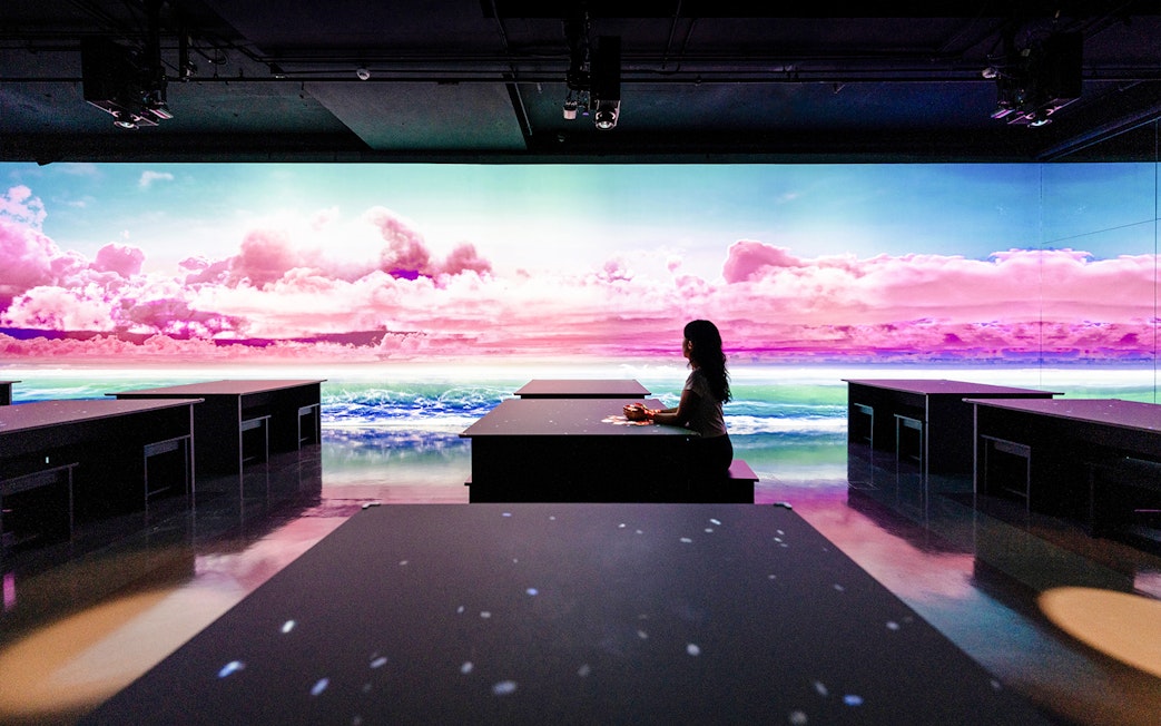 Person seated at ARTE TEA BAR, Arte Museum Dubai, with vibrant digital ocean and sky display.