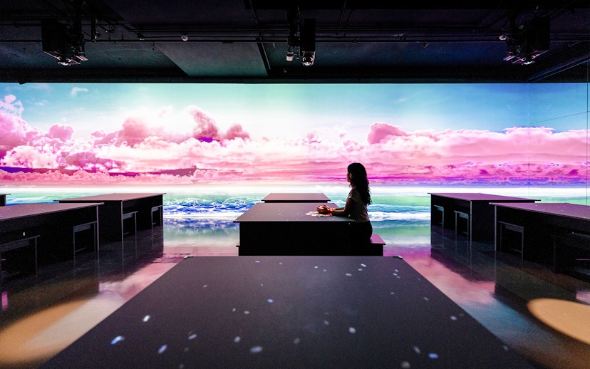 Person seated at ARTE TEA BAR, Arte Museum Dubai, with vibrant digital ocean and sky display.