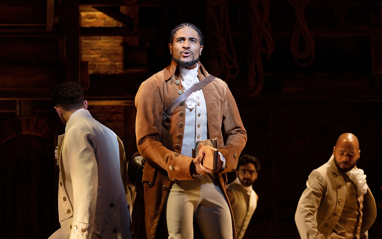 Performer in period costume on stage during Hamilton musical.