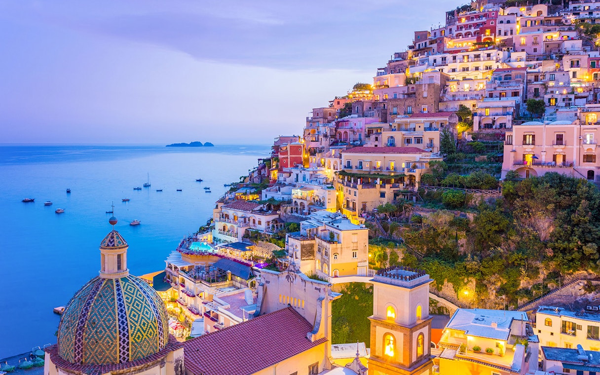 Colorful hillside buildings in Positano overlooking the sea at dusk, near the Naples to Sorrento train route.