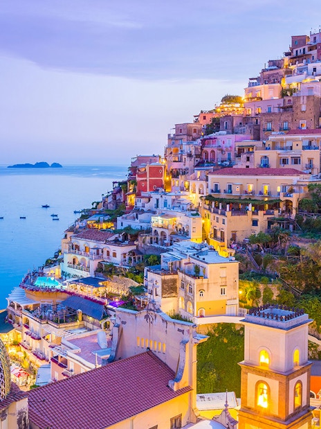 Colorful hillside buildings in Positano overlooking the sea at dusk, near the Naples to Sorrento train route.