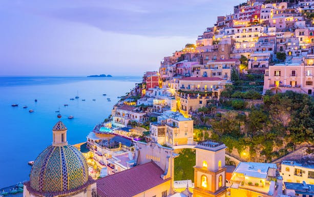 Colorful hillside buildings in Positano overlooking the sea at dusk, near the Naples to Sorrento train route.