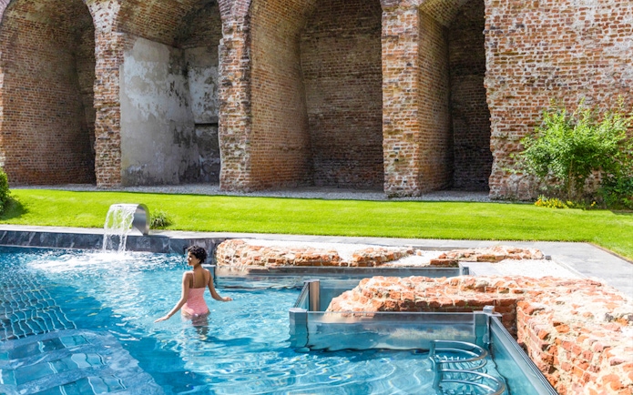 Visitor enjoying the pool at QC Terme Milano Resort & Spa with historic brick arches.
