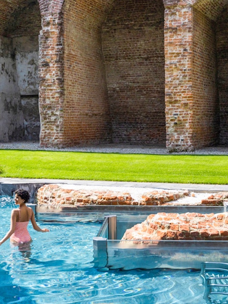 Visitor enjoying the pool at QC Terme Milano Resort & Spa with historic brick arches.