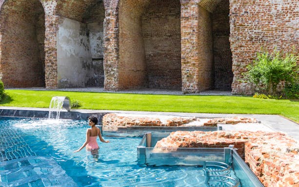 Visitor enjoying the pool at QC Terme Milano Resort & Spa with historic brick arches.